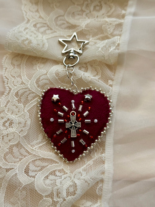 Heart-shaped embroidered pendant keychain with star and cross designs on a lace background