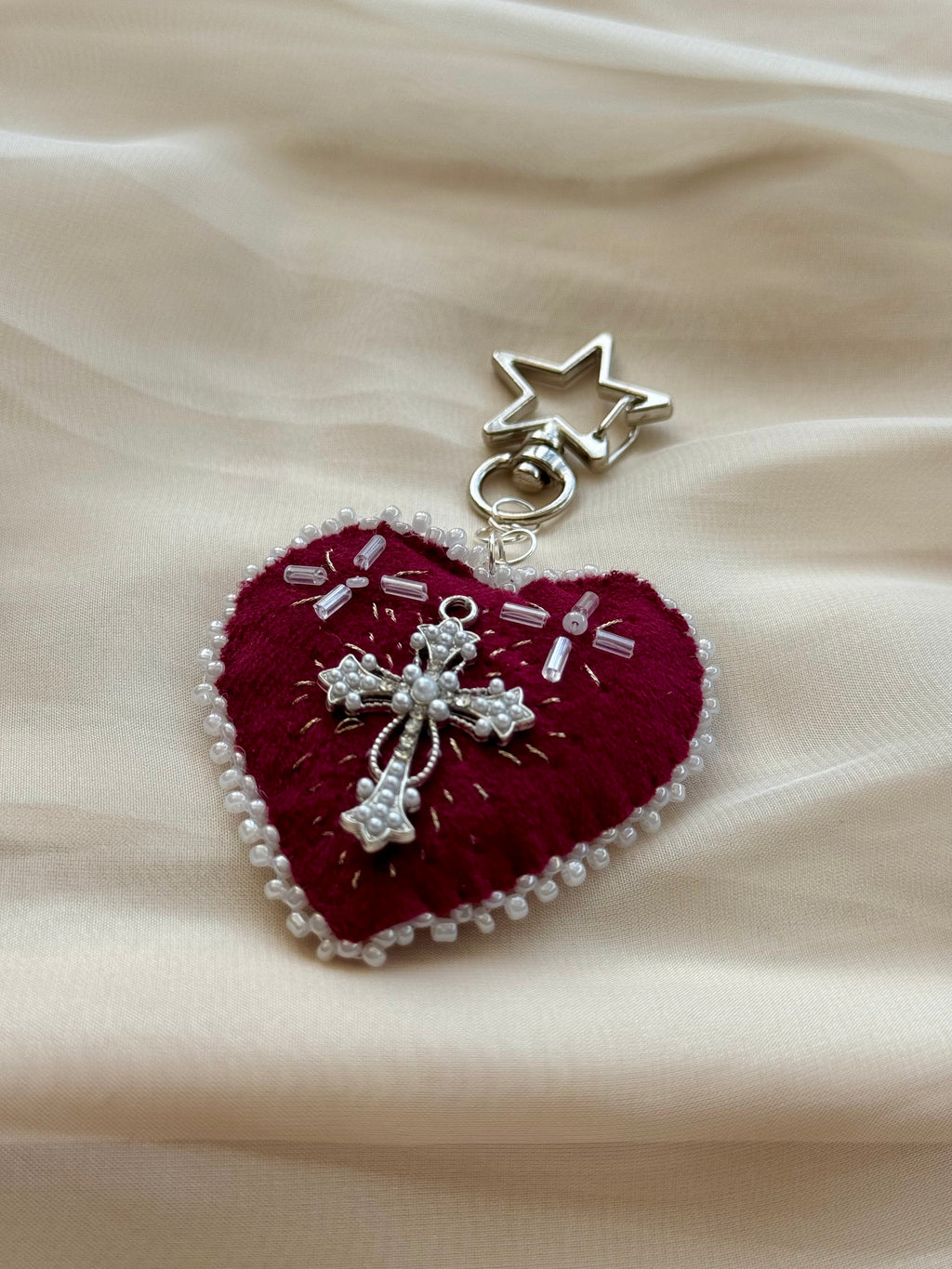 Heart-shaped embroidered pendant keychain with star and cross designs on a lace background