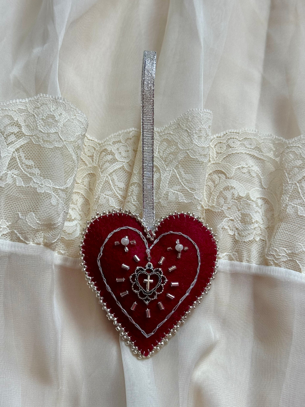 Decorative red heart with silver embellishments on a white lace background