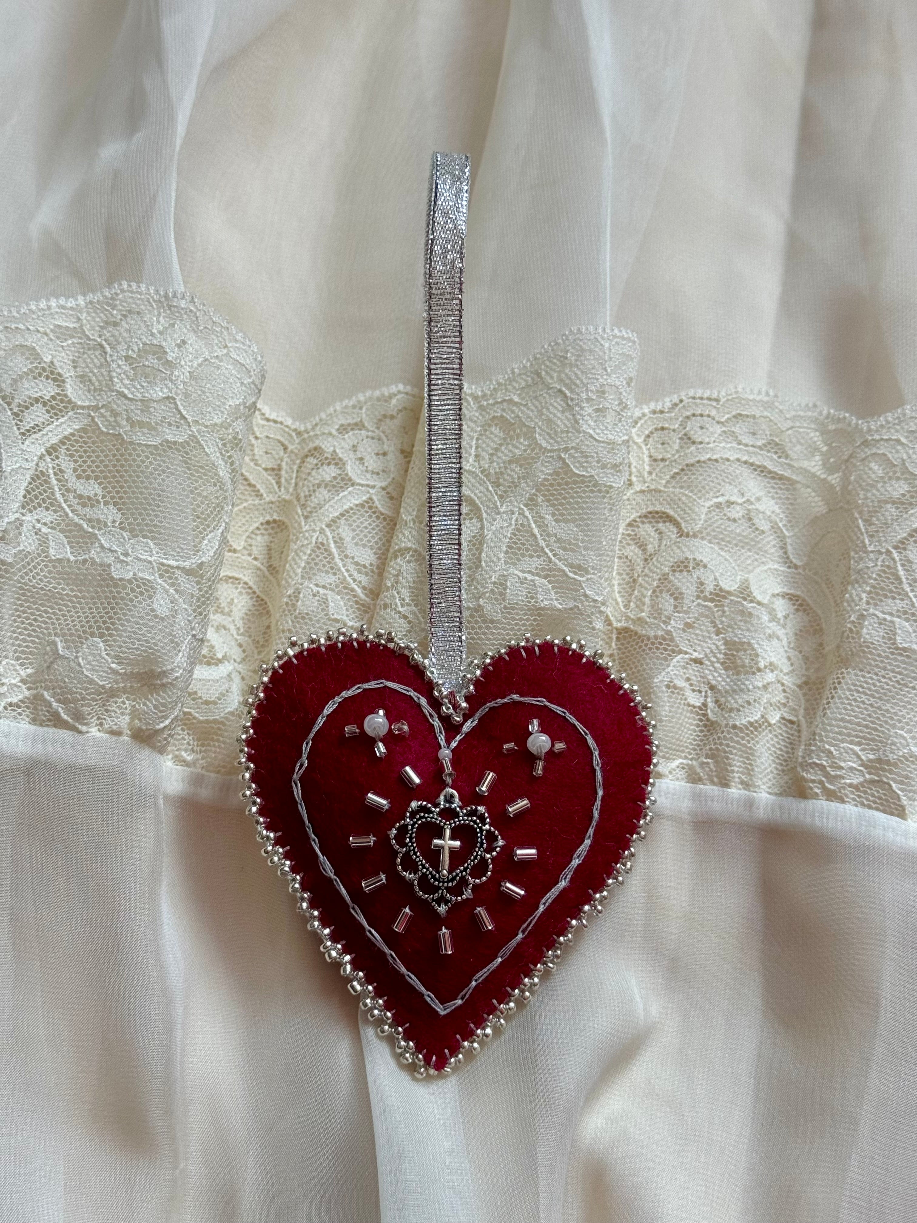 Decorative red heart with silver embellishments on a white lace background