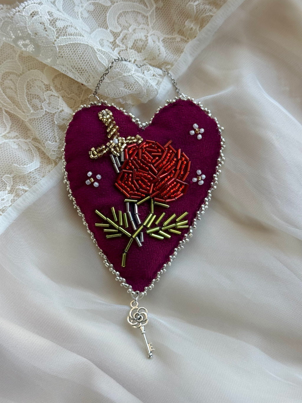Embroidered heart-shaped decoration with a rose design on a white lace background