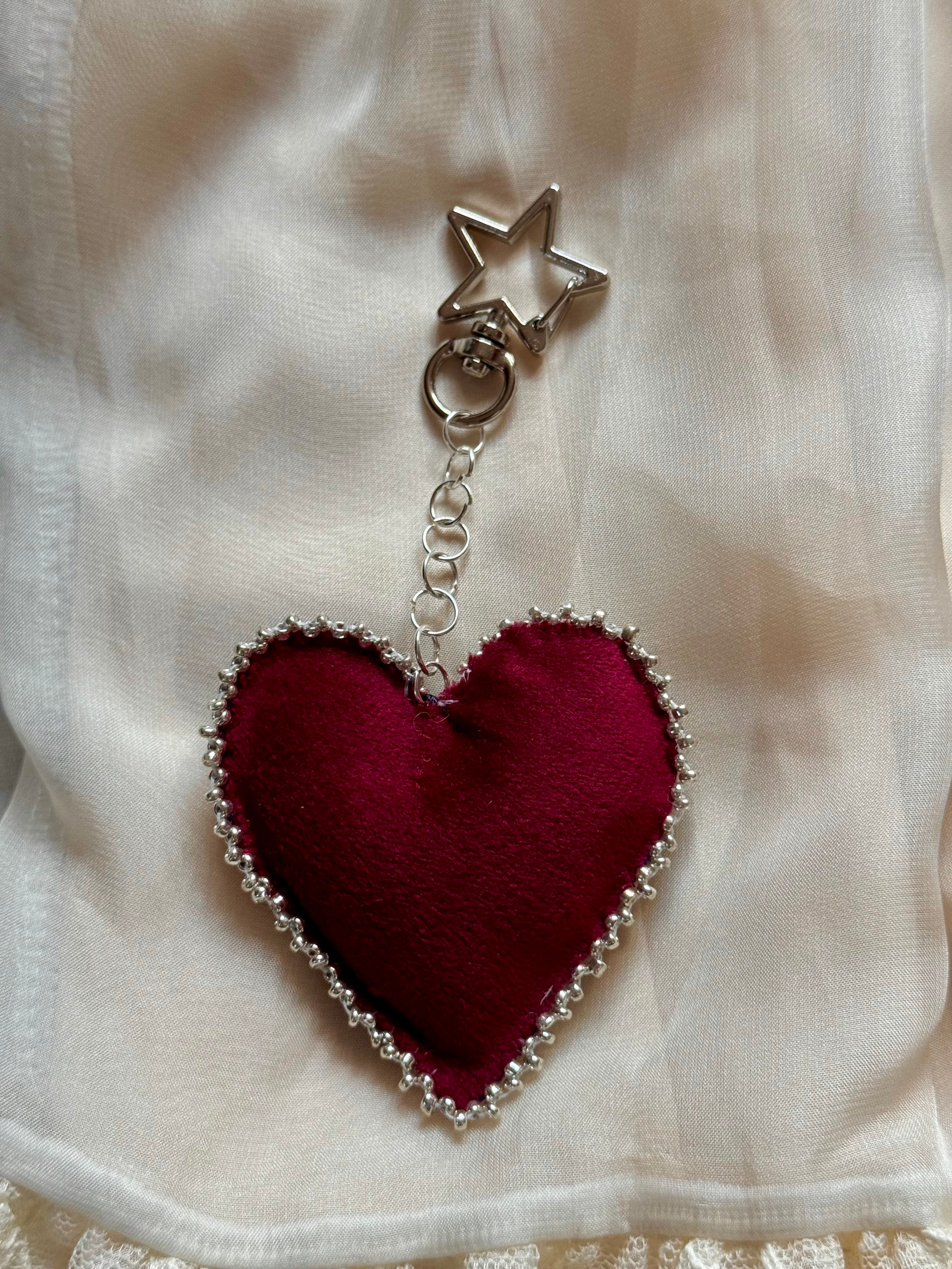 Heart-shaped keychain with star charm on a white fabric background