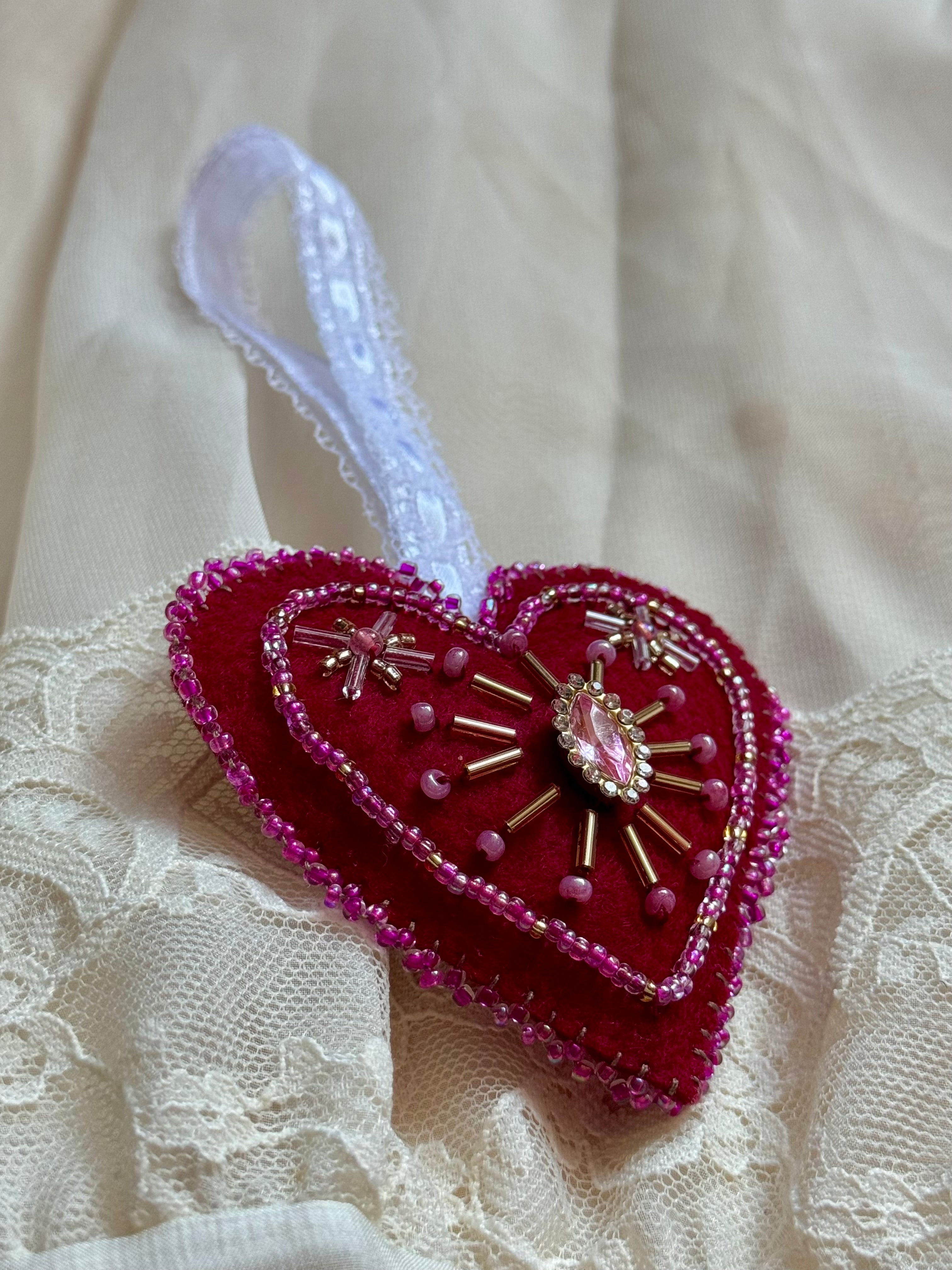 Decorative heart ornament with beads and a gemstone on a lace background