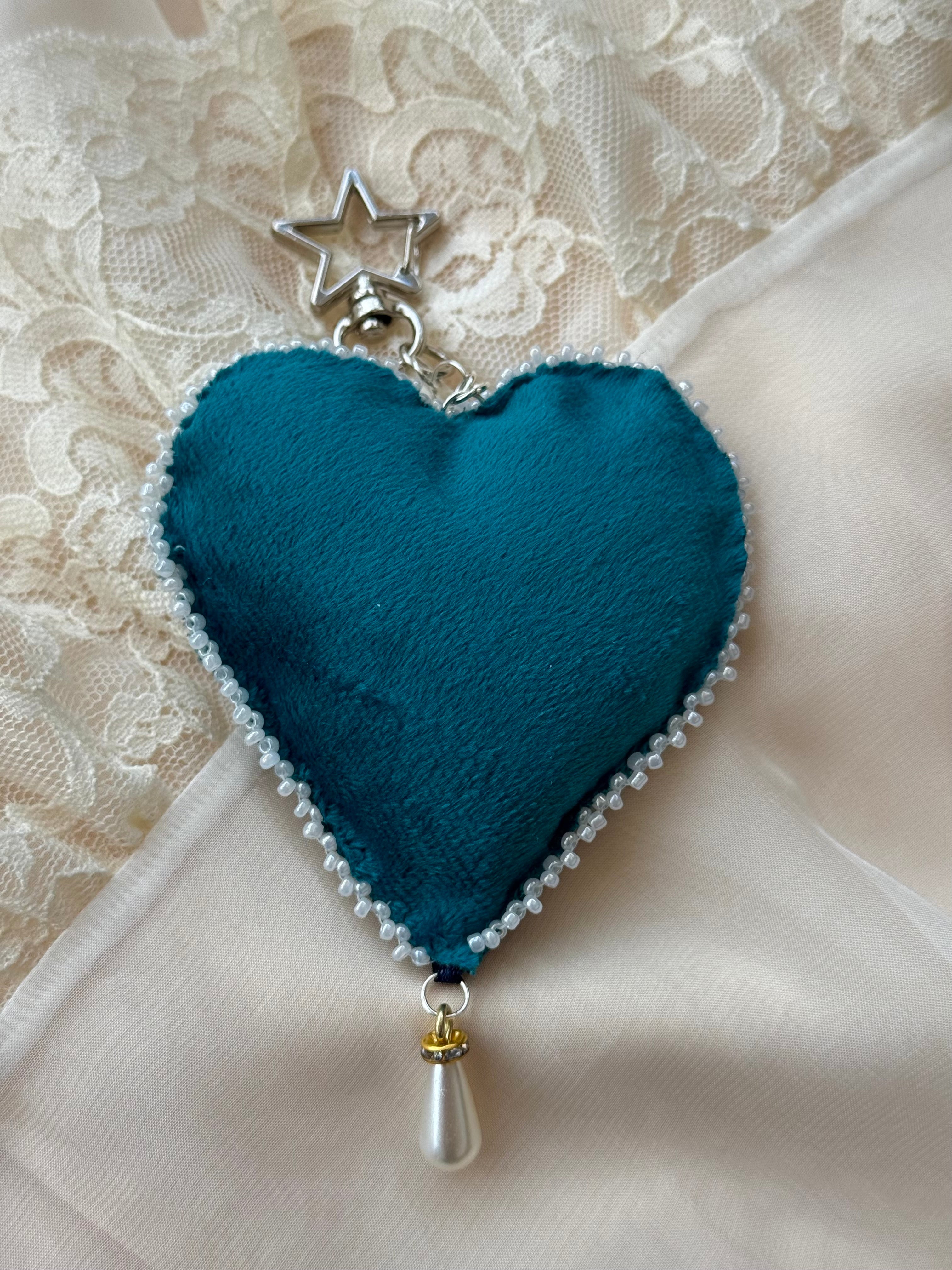 Teal heart-shaped decorative item with a star and teardrop on a lace background