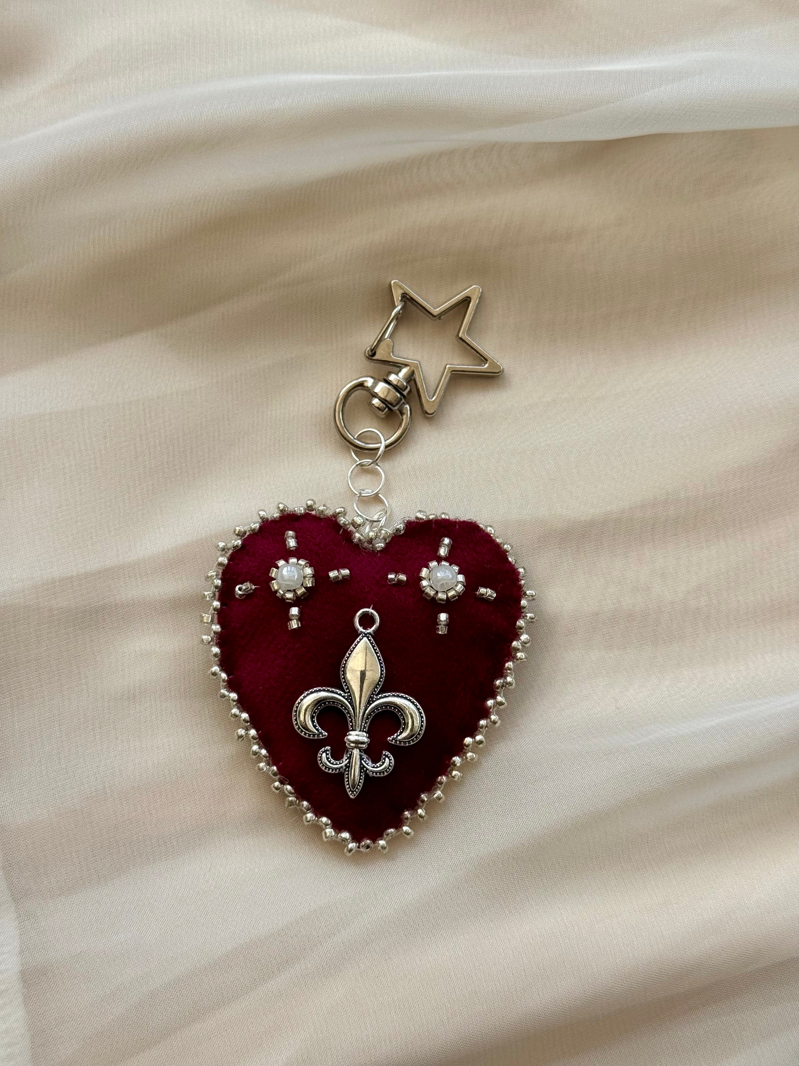 Heart-shaped fleur-de-lis pendant keychain with star charm on lace fabric