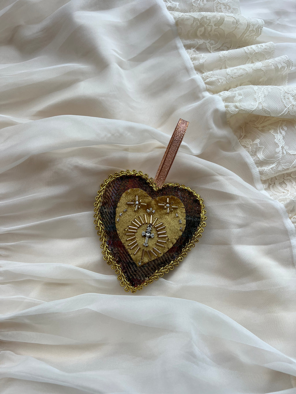 Heart-shaped decorative brooch on a white fabric background