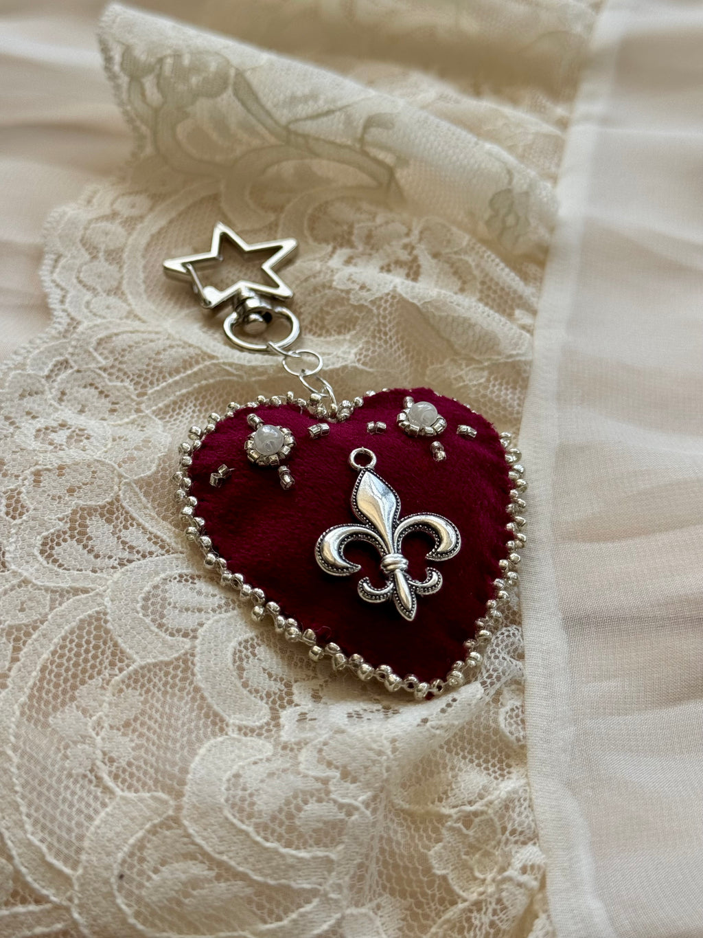 Heart-shaped fleur-de-lis pendant keychain with star charm on lace fabric