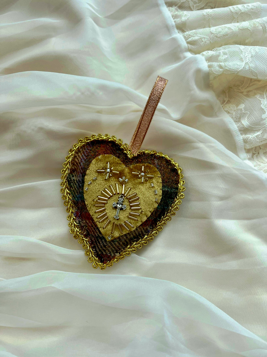 Decorative heart-shaped ornament with intricate designs on a white fabric background