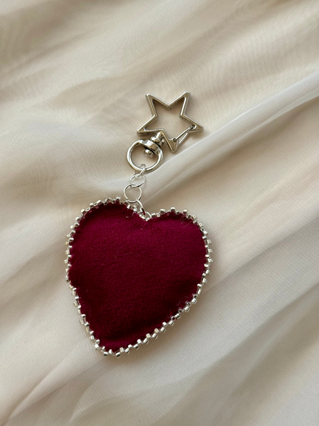 Heart-shaped keychain with star charm on a beige fabric background