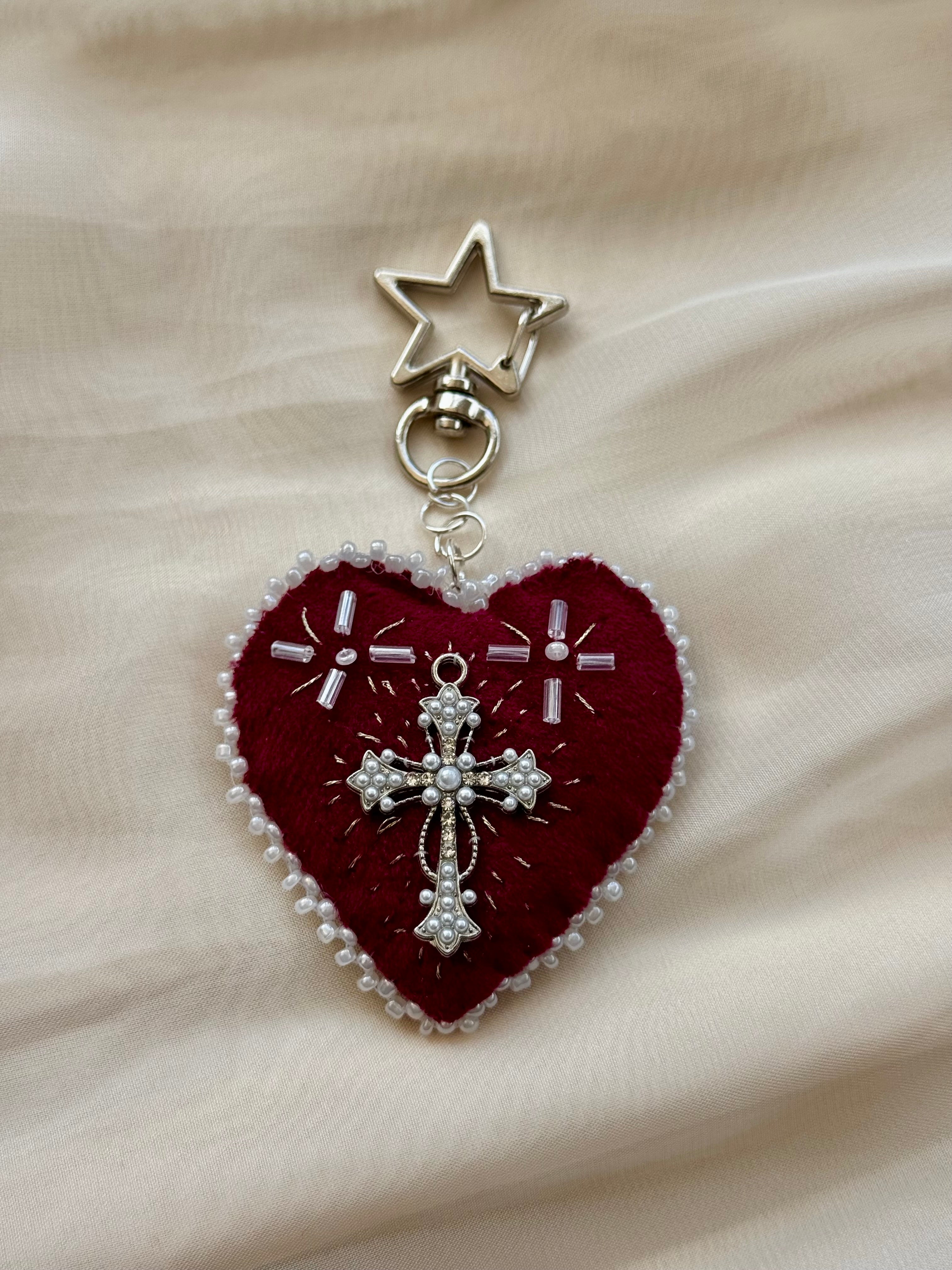Heart-shaped embroidered pendant keychain with star and cross designs on a lace background