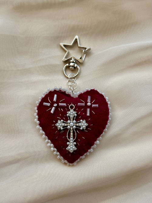 Heart-shaped embroidered pendant keychain with star and cross designs on a lace background