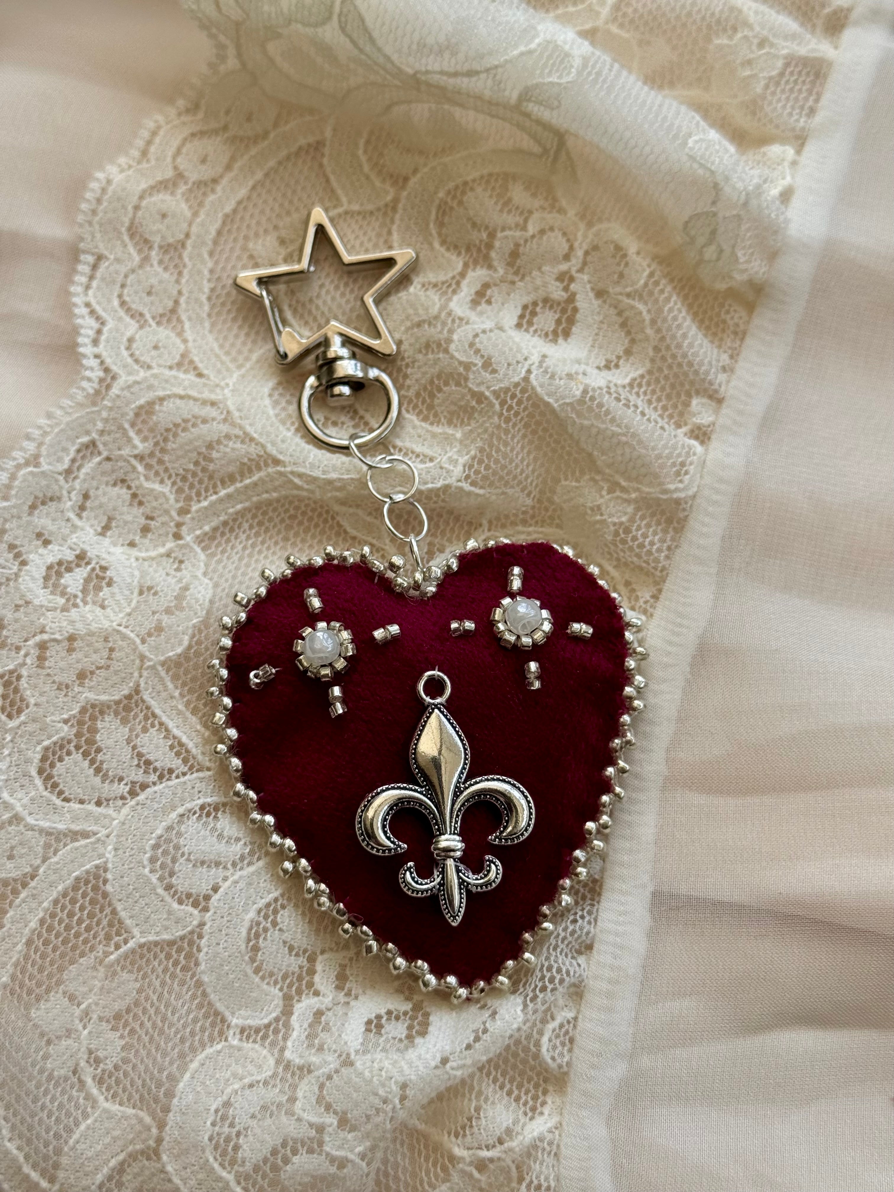 Heart-shaped fleur-de-lis pendant keychain with star charm on lace fabric