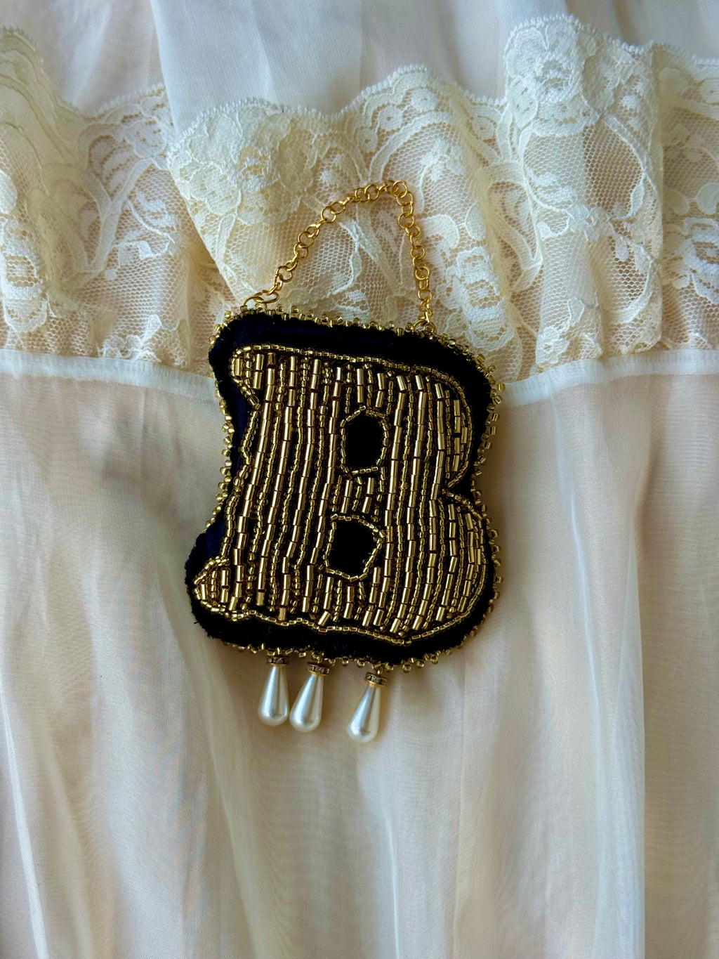 Detailed view of 14 hours of intricate gold beadwork and metallic gold-work on a handmade Tudor-inspired ornament.