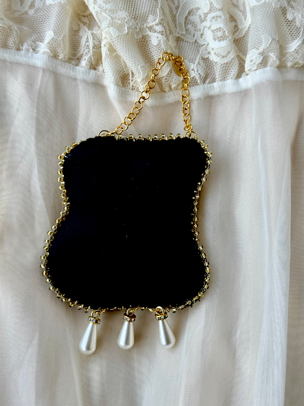 The reverse of the Boleyn in Triumph ornament showing the hand-stitched construction, firm luxury velvet backing, gold beaded edging and the secure attachment of the hanging chain and teardrop pearls.