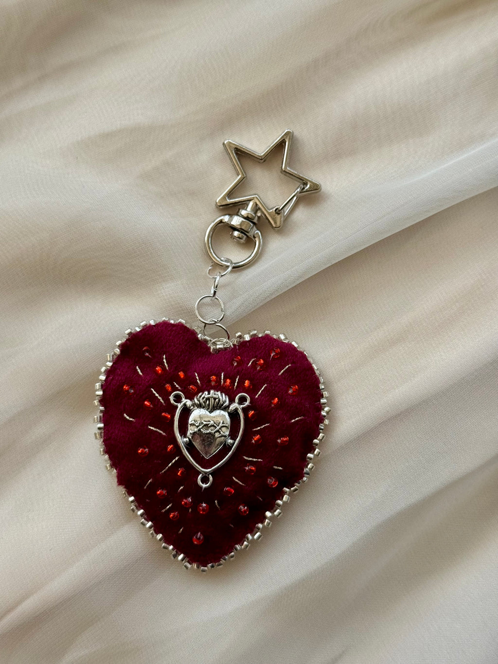 Heart-shaped keychain with star charm on a beige fabric background