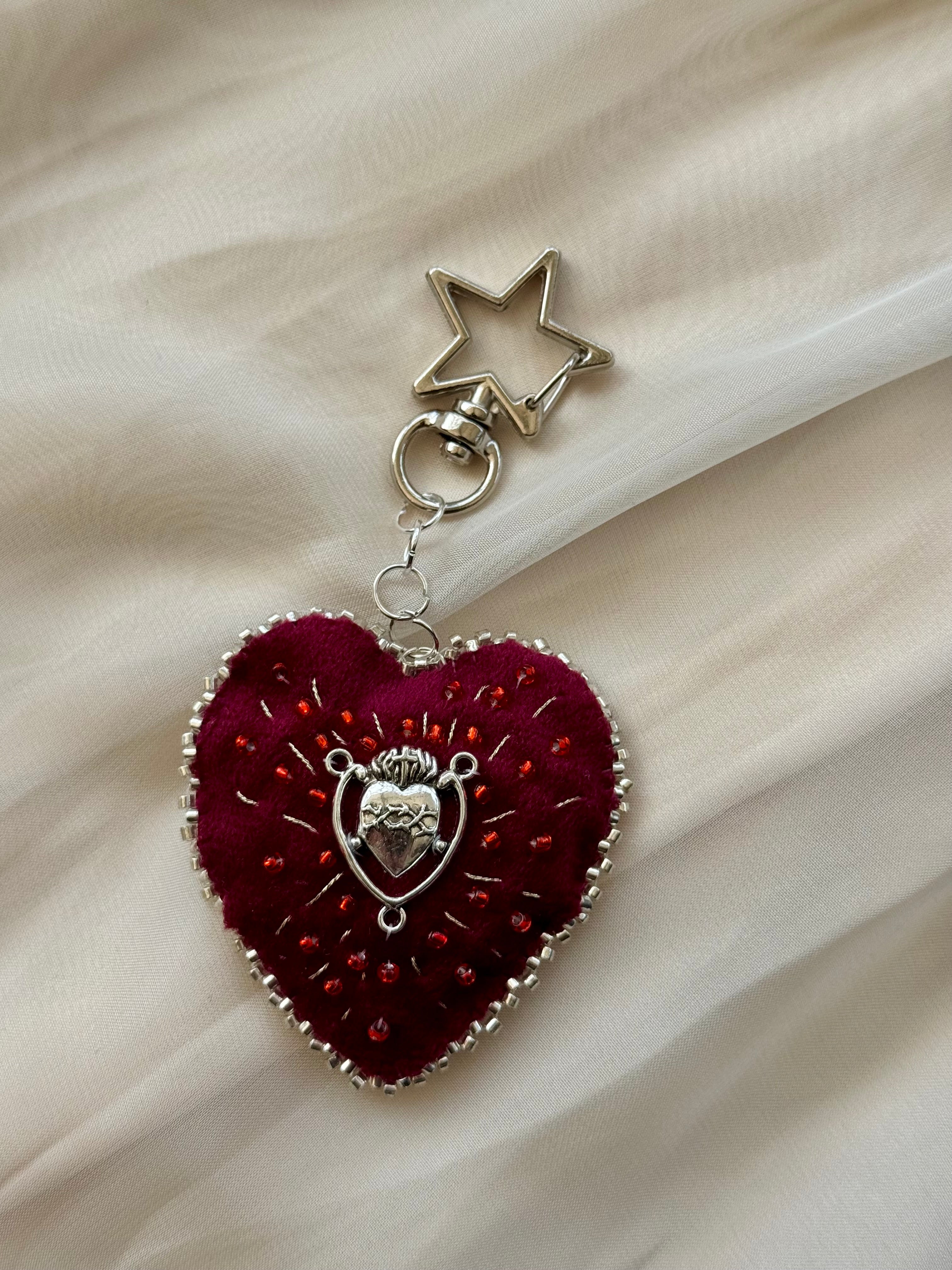 Heart-shaped keychain with star charm on a beige fabric background