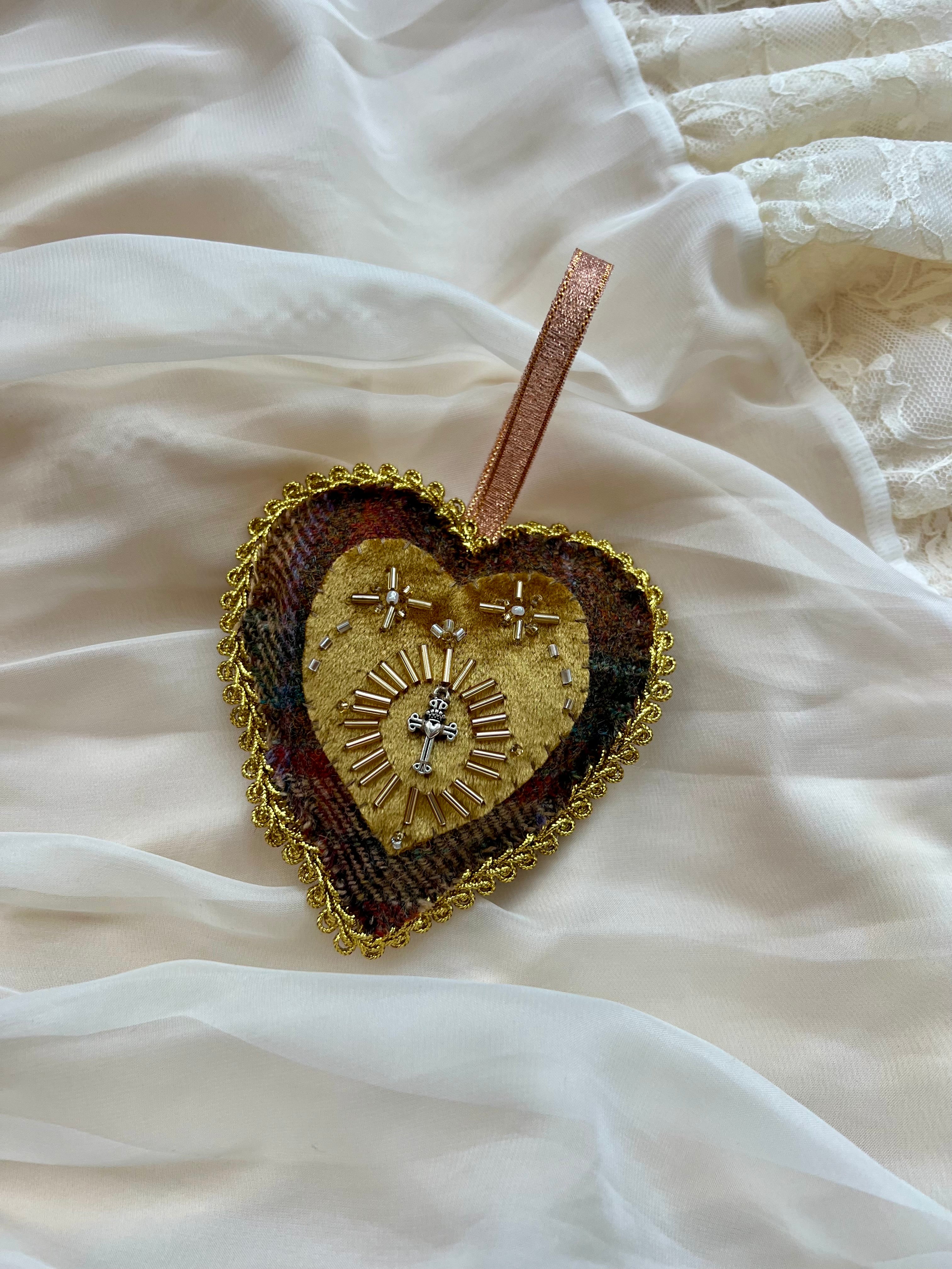 Heart-shaped decorative item with gold and brown colors on a white fabric background