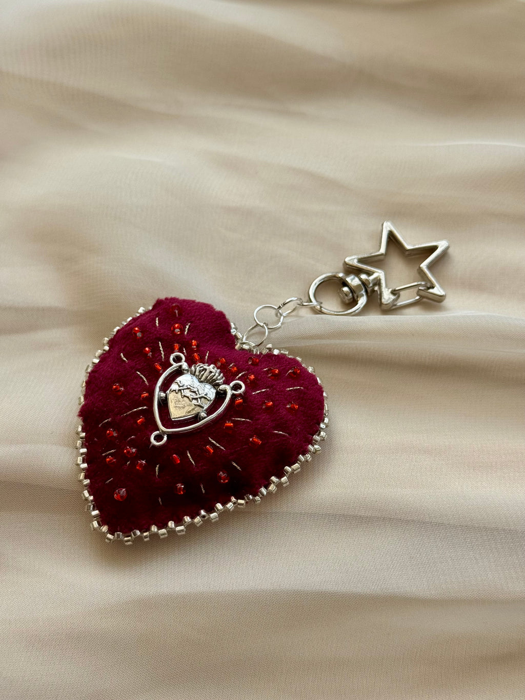 Heart-shaped pendant with star charm on a beige fabric background