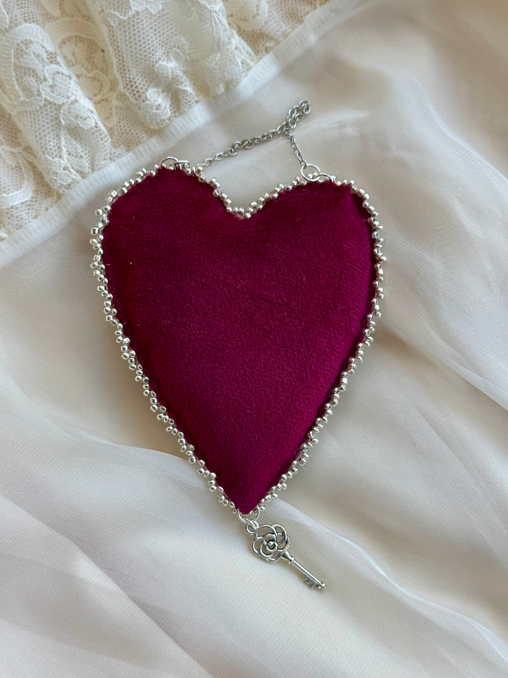 Heart-shaped pendant with a key on a white lace background