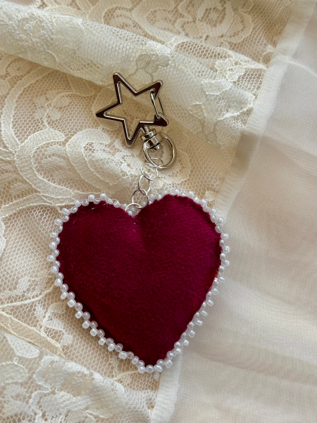 Heart-shaped embroidered pendant keychain with star and cross designs on a lace background