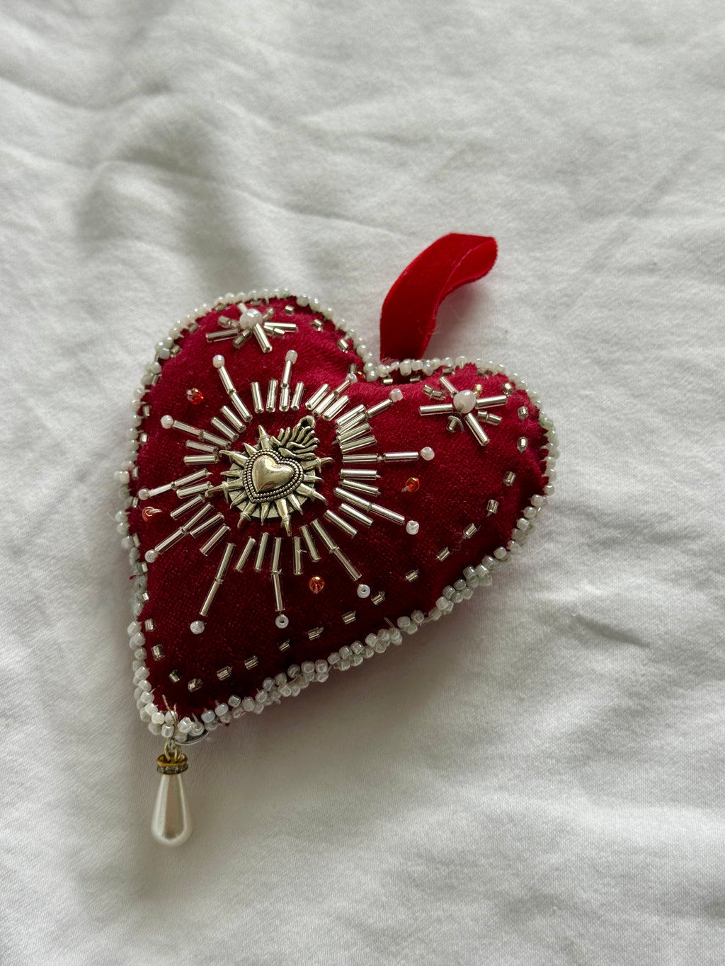 Decorative heart ornament with beadwork on a white fabric background