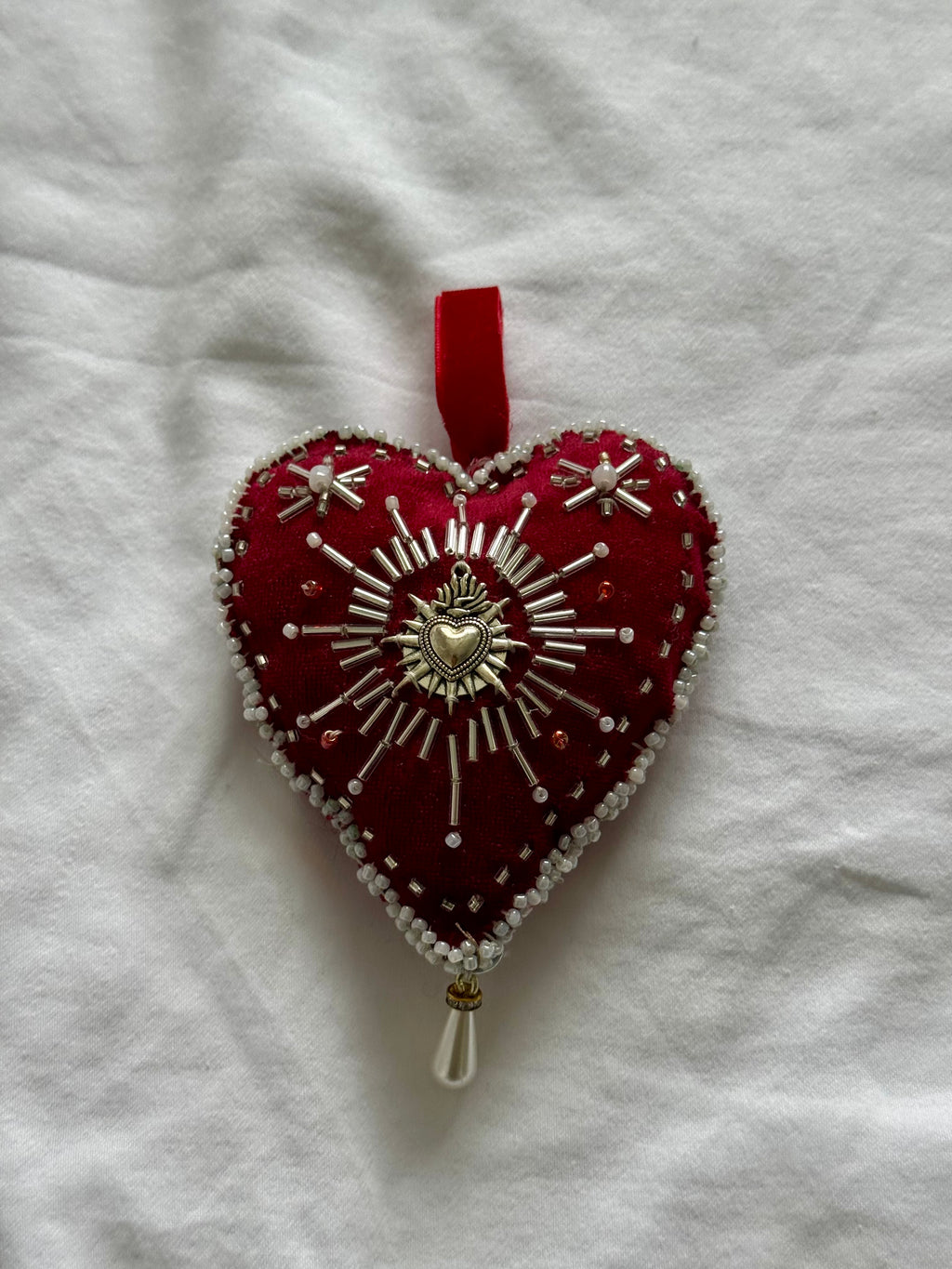 Decorative heart ornament with beadwork on a white fabric background