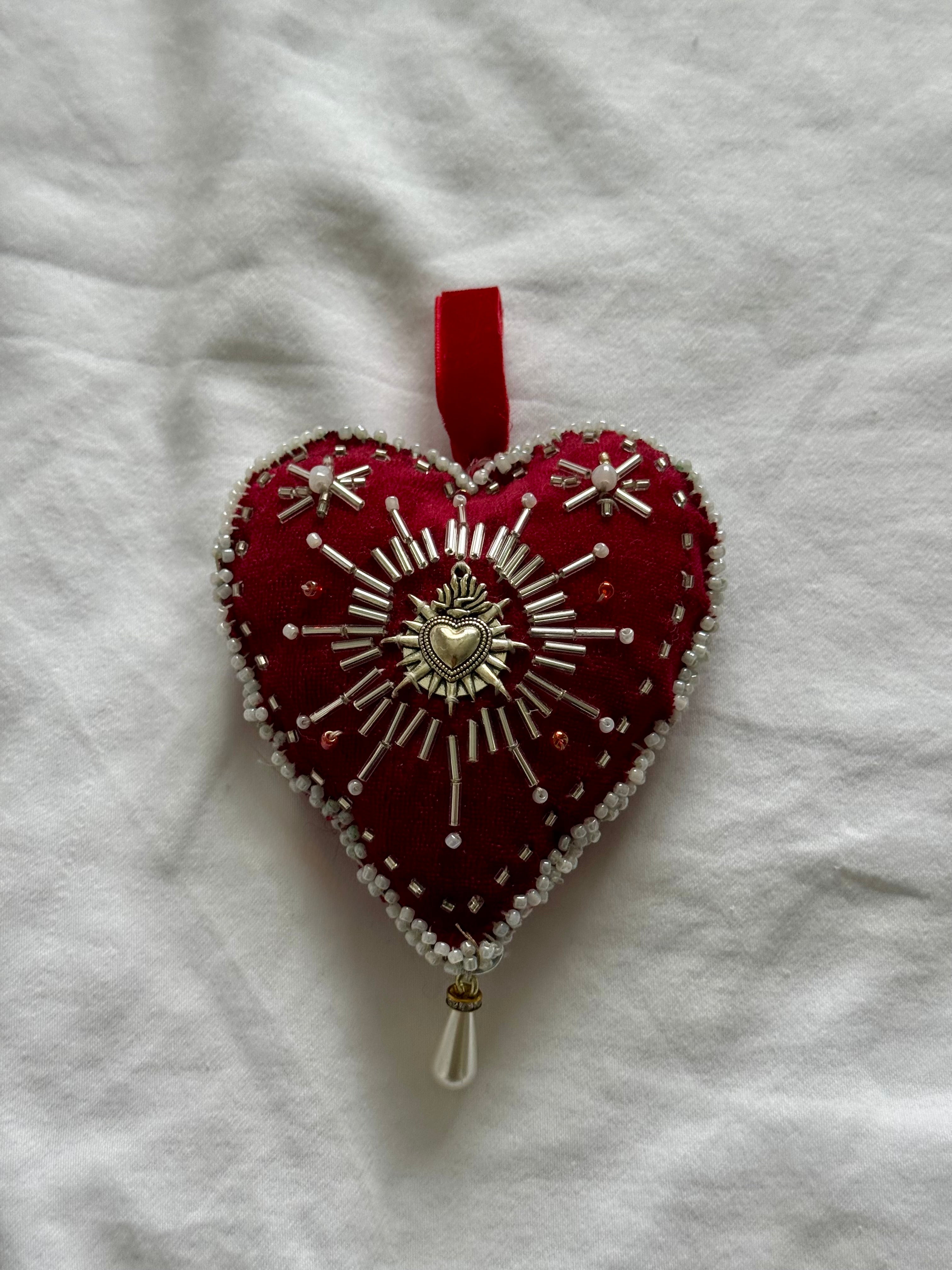 Decorative heart ornament with beadwork on a white fabric background