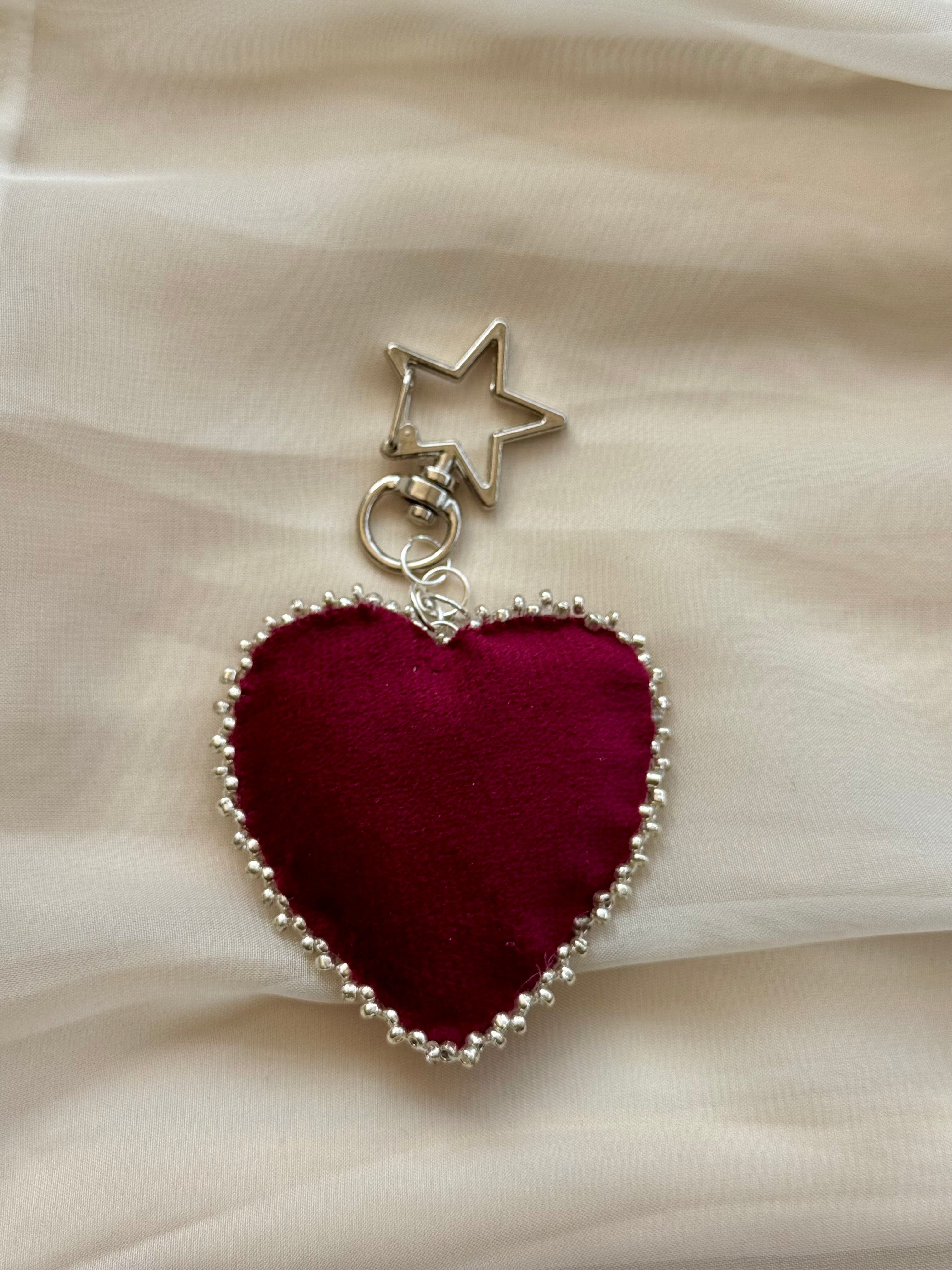 Heart-shaped keychain with star charm on a beige fabric background