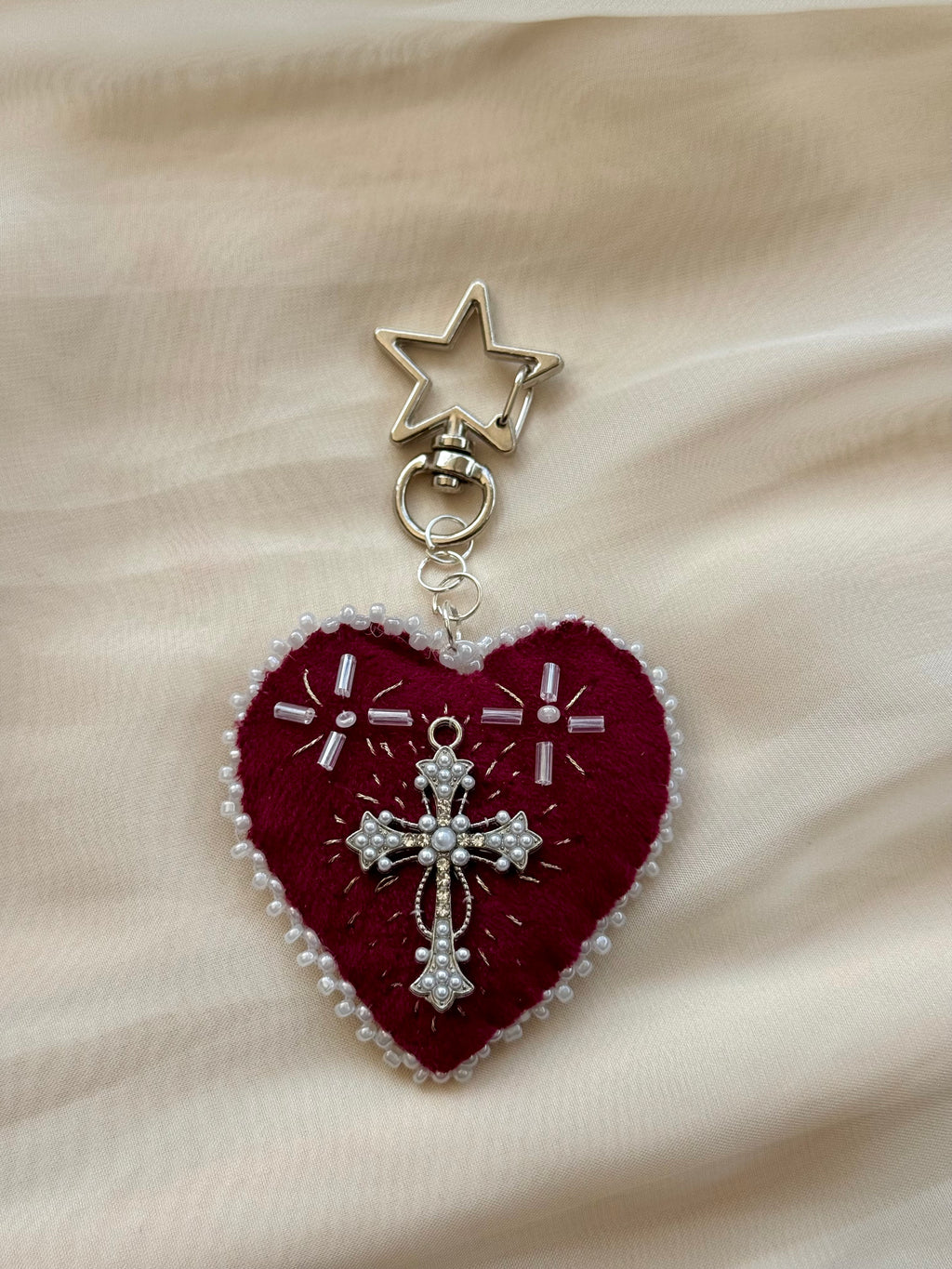 Heart-shaped embroidered pendant keychain with star and cross designs on a lace background
