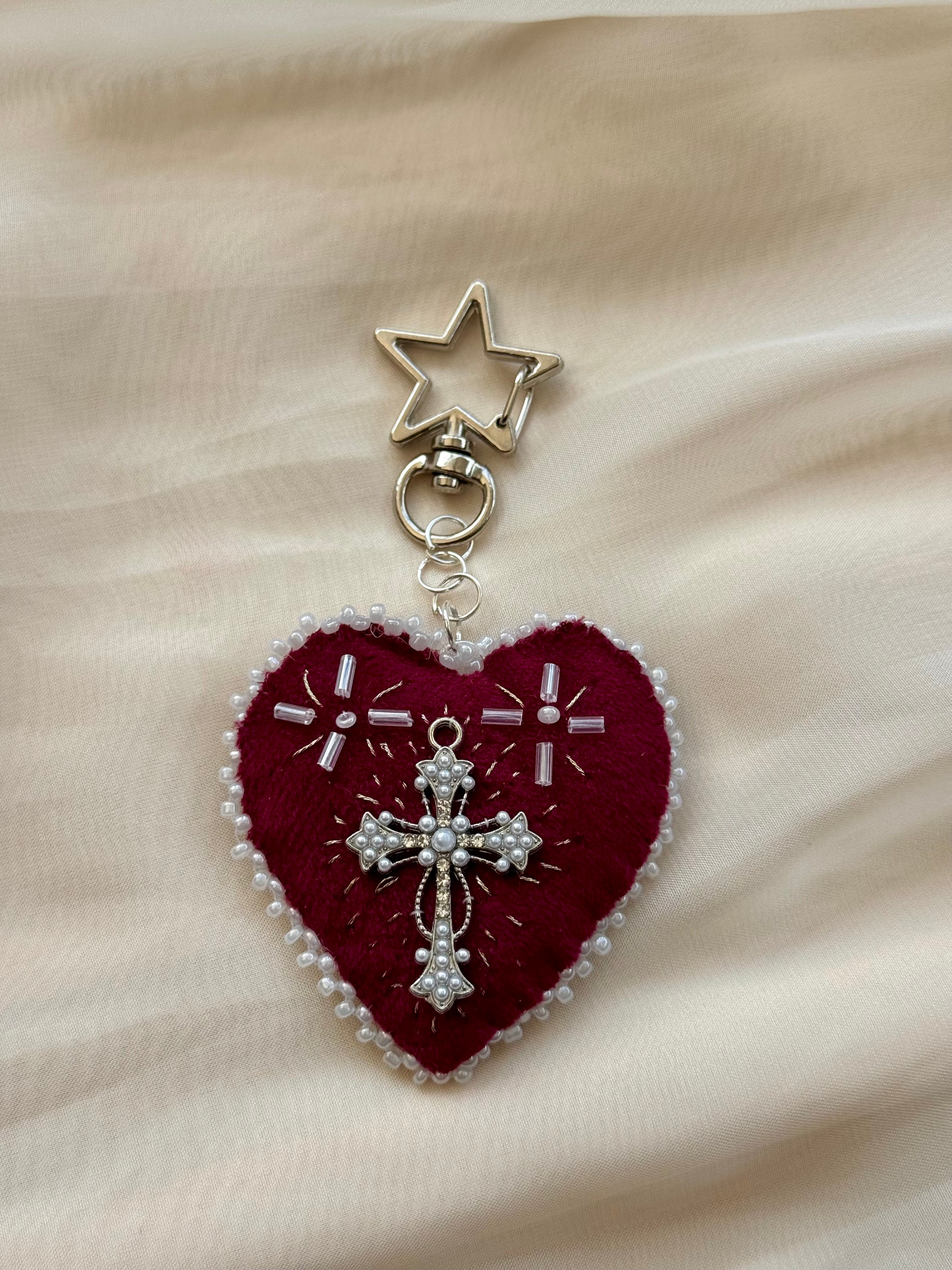 Heart-shaped embroidered pendant keychain with star and cross designs on a lace background