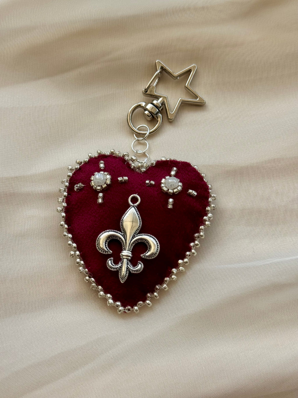 Heart-shaped fleur-de-lis pendant keychain with star charm on lace fabric