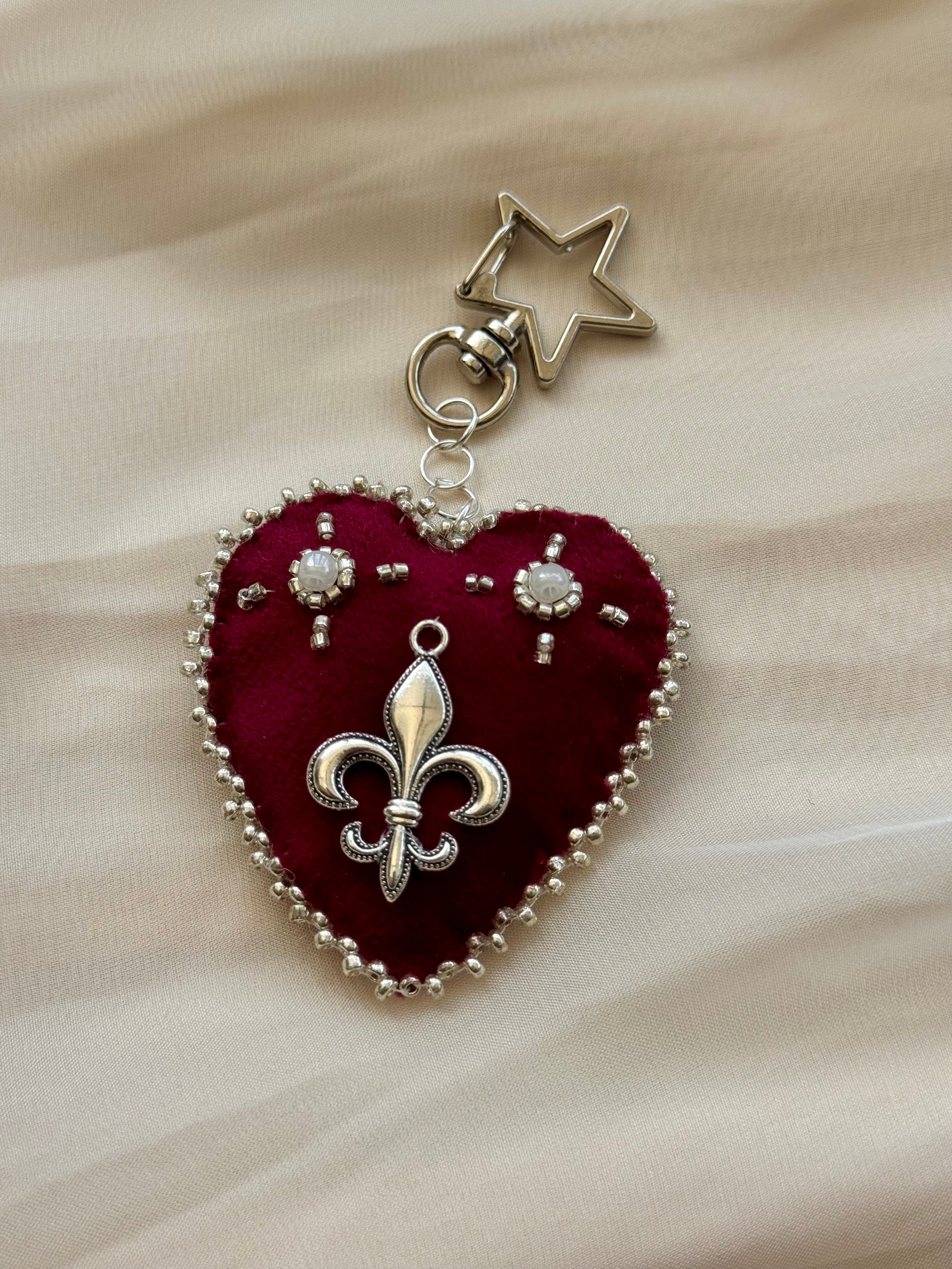 Heart-shaped fleur-de-lis pendant keychain with star charm on lace fabric
