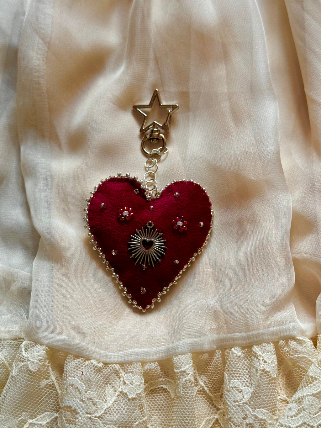 Heart-shaped pendant with star charm on a white fabric background