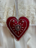 Red heart-shaped ornament with silver details on a white lace background