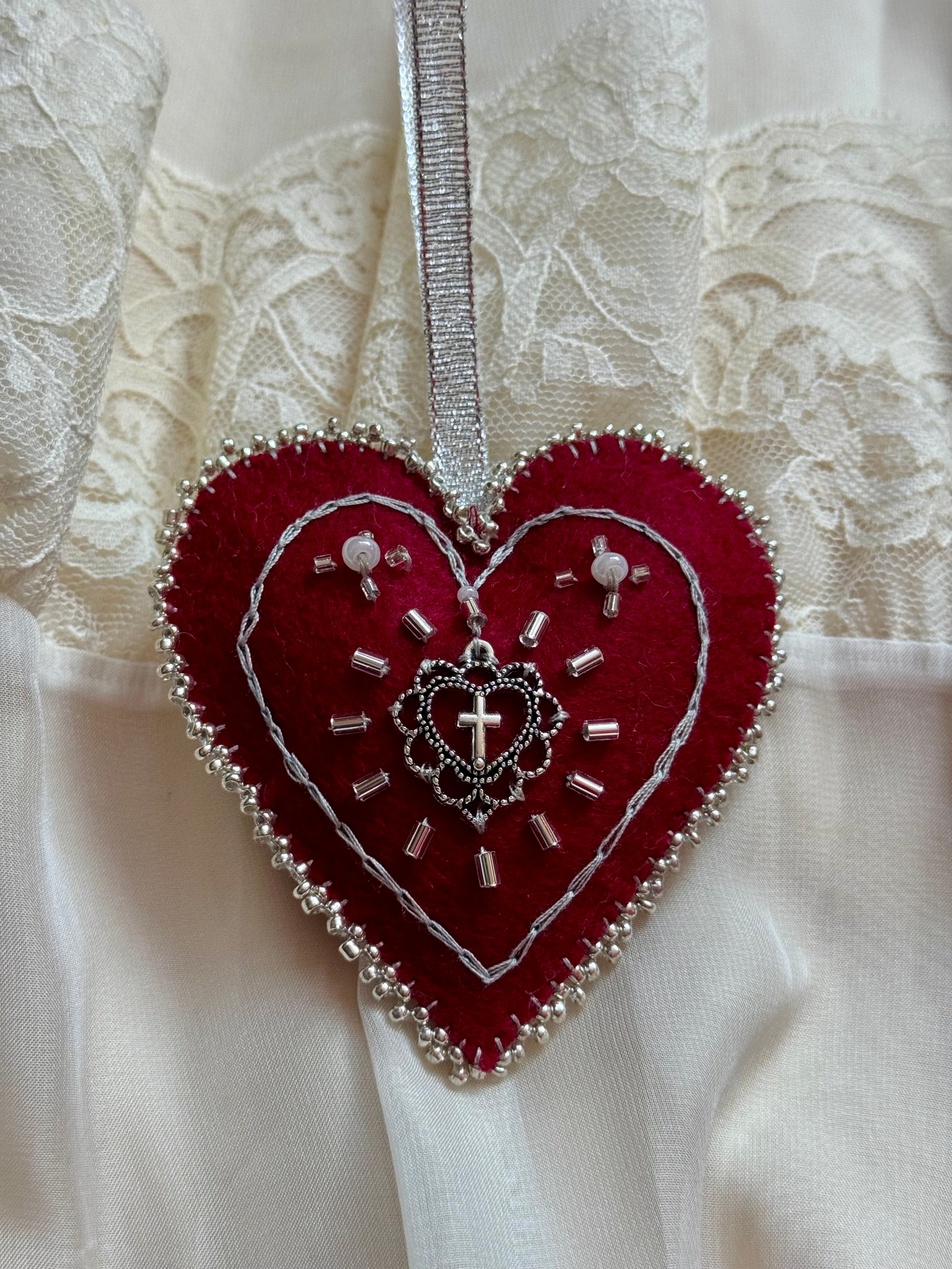 Red heart-shaped ornament with silver details on a white lace background