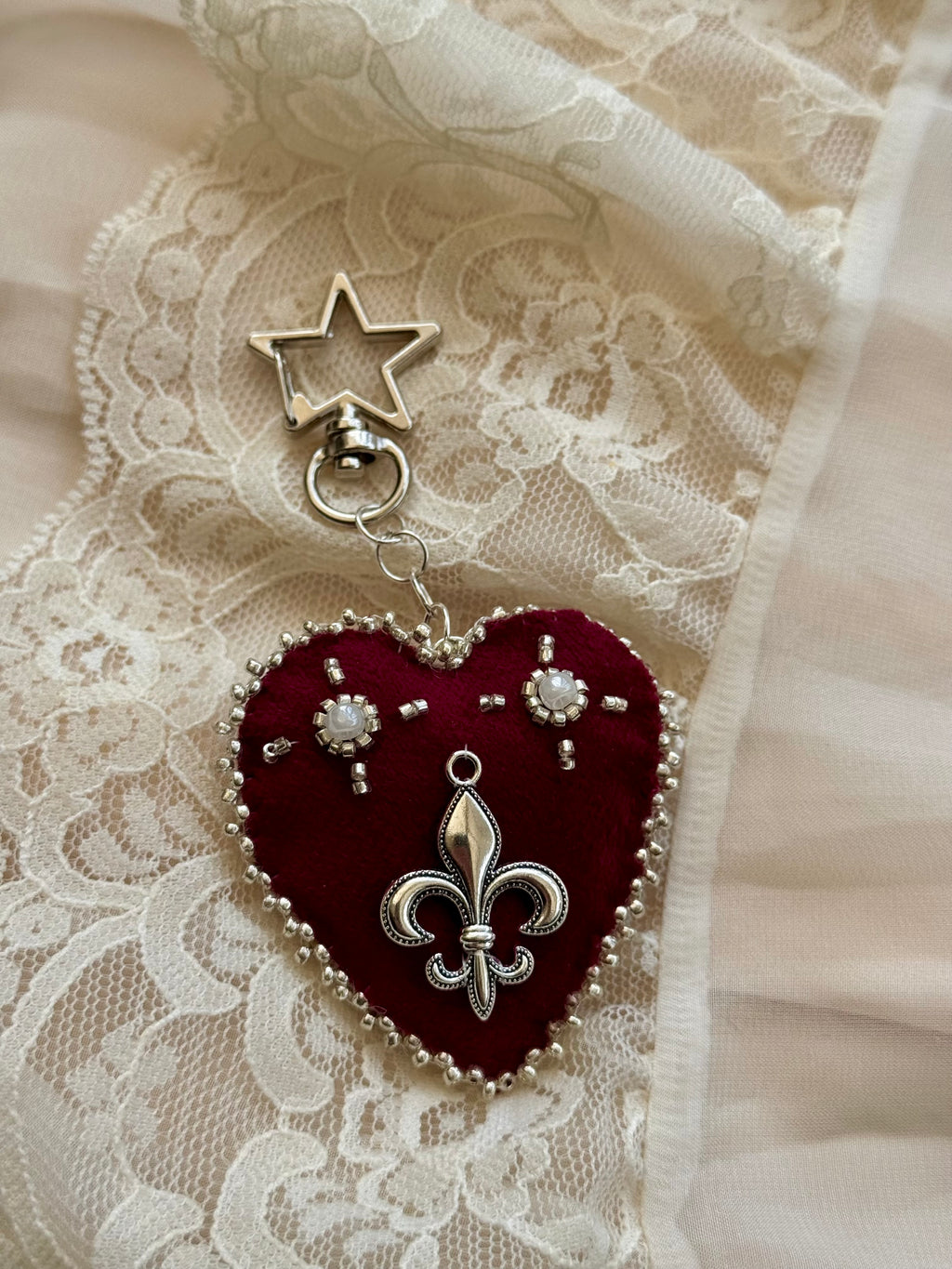 Heart-shaped fleur-de-lis pendant keychain with star charm on lace fabric