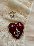 Heart-shaped fleur-de-lis pendant keychain with star charm on lace fabric