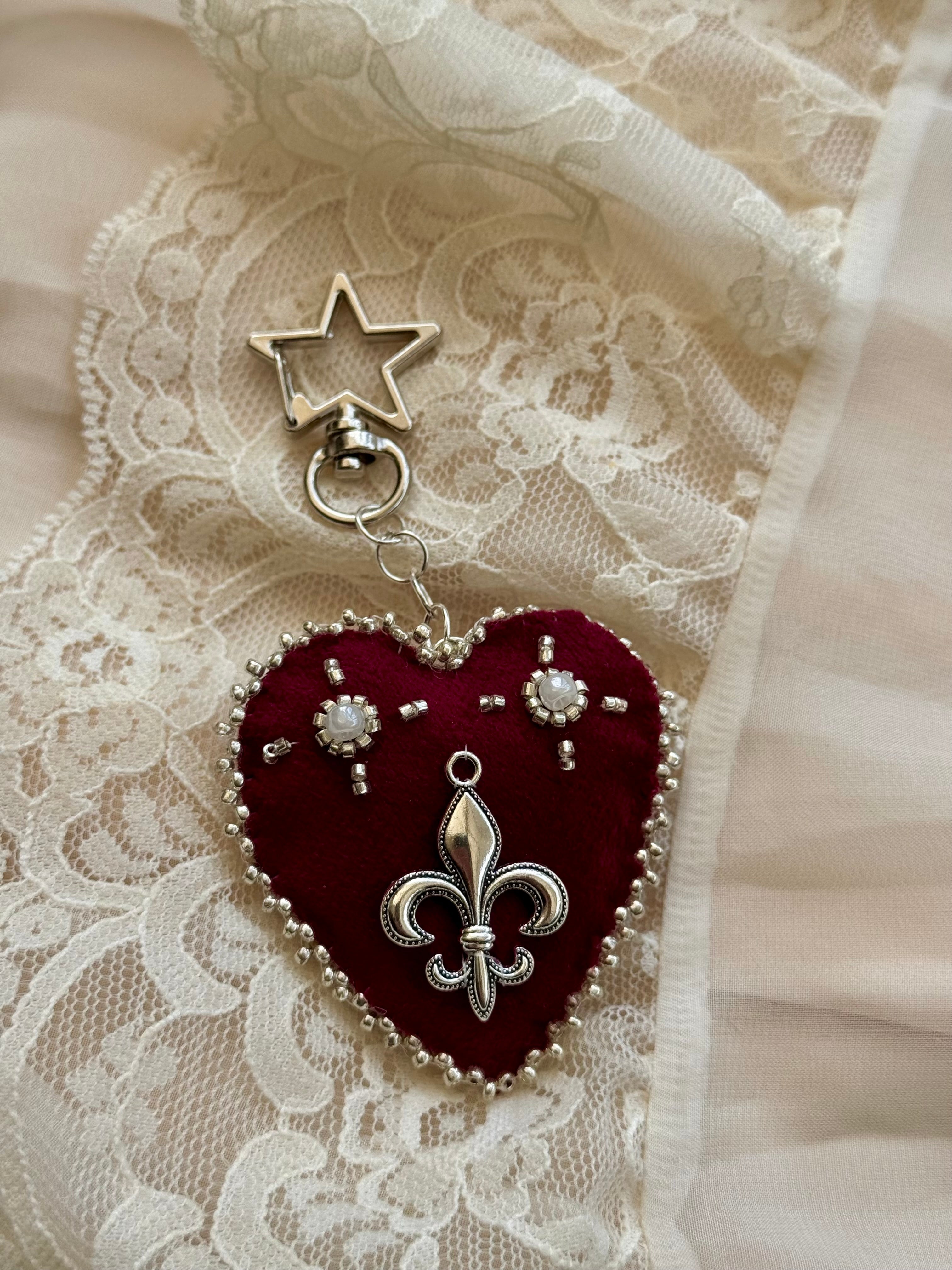 Heart-shaped fleur-de-lis pendant keychain with star charm on lace fabric