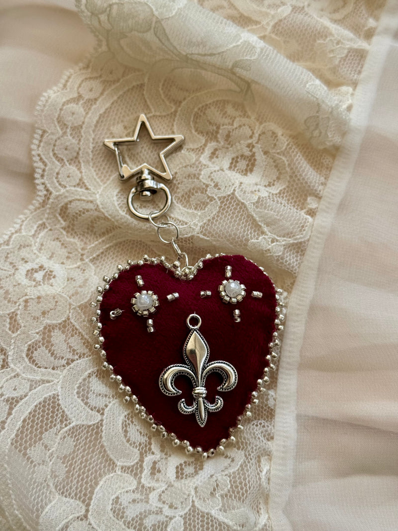 Heart-shaped fleur-de-lis pendant keychain with star charm on lace fabric
