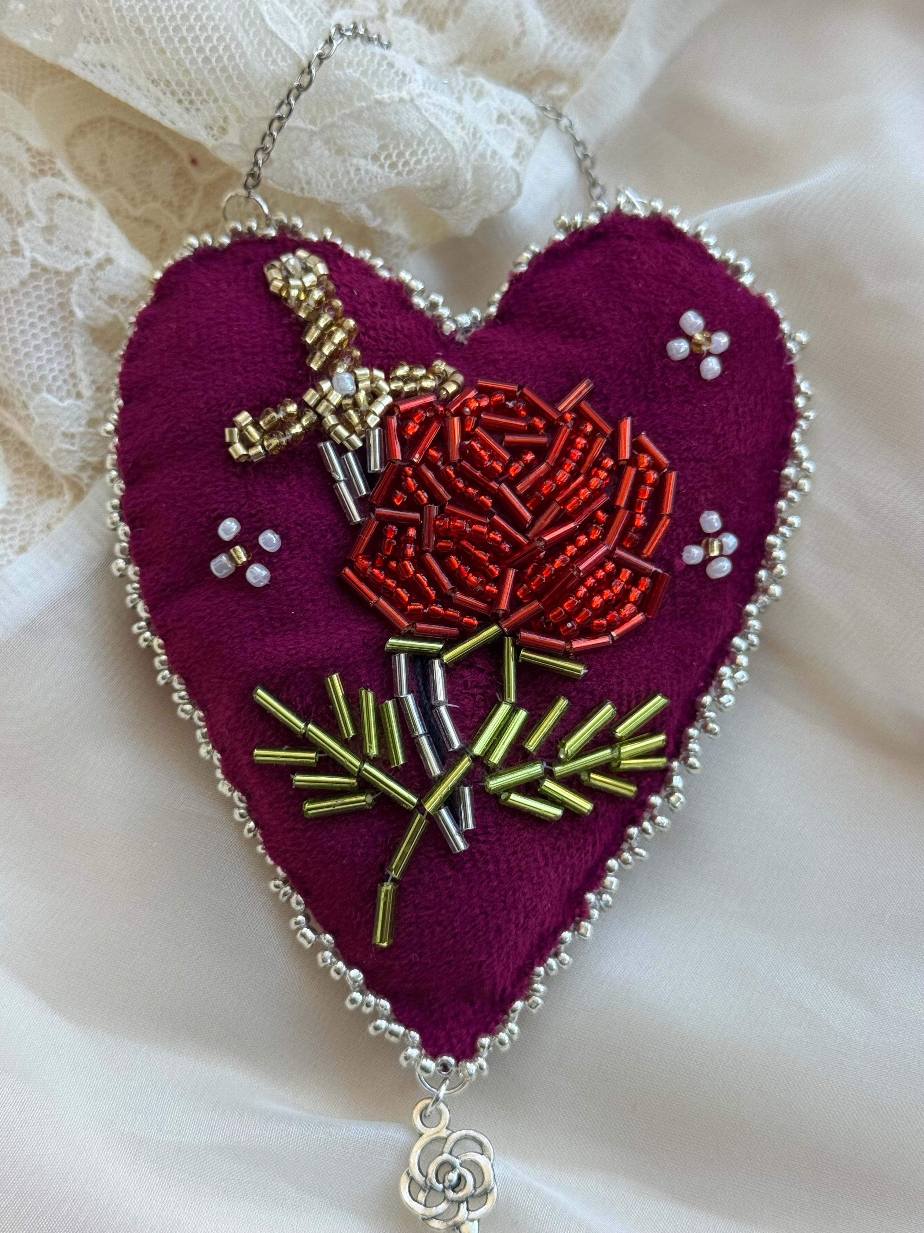 Heart-shaped embroidered pendant with a rose design on a white lace background