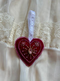 Heart-shaped ornament with a pink gem on a white lace background