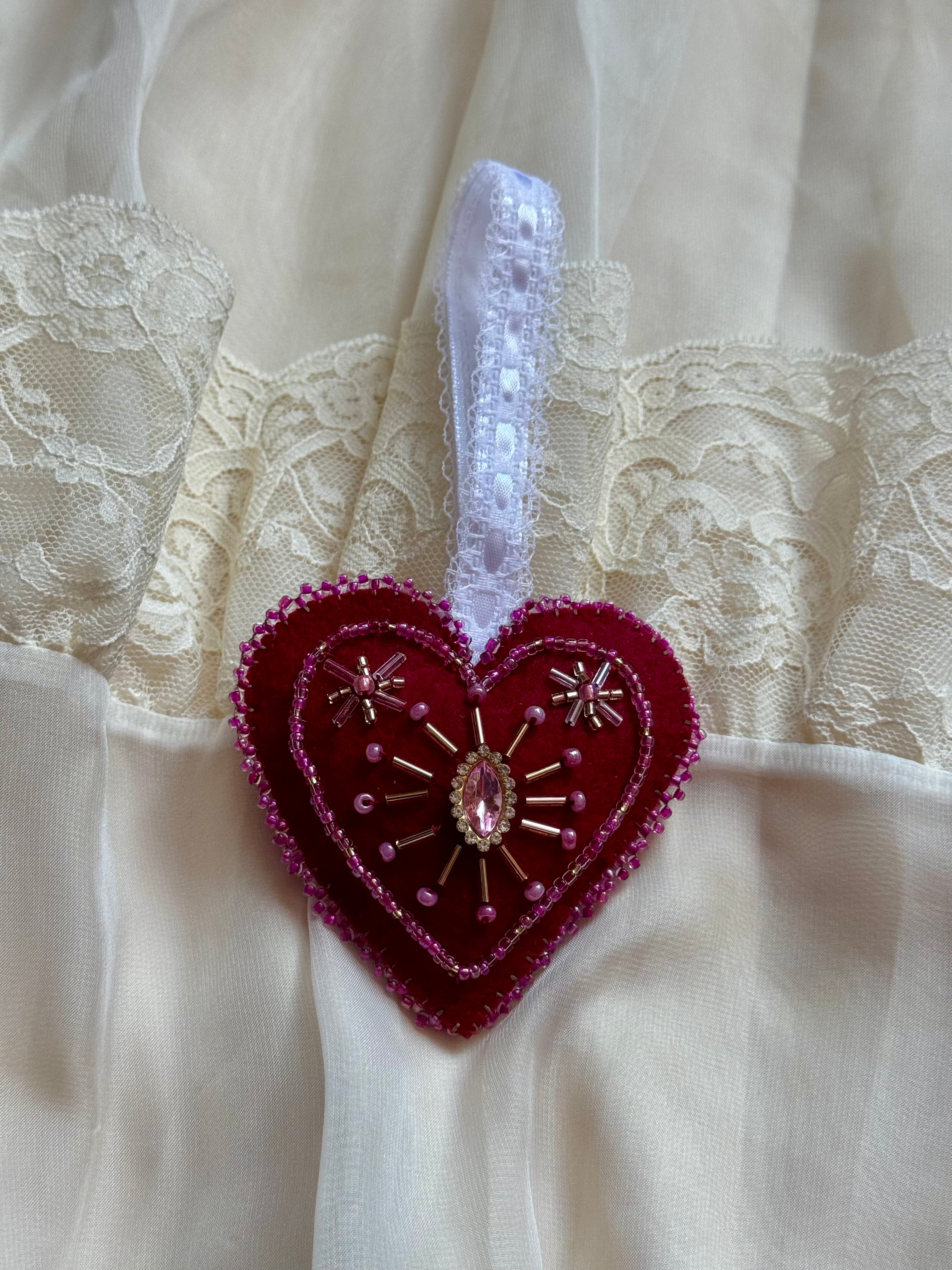 Heart-shaped ornament with a pink gem on a white lace background