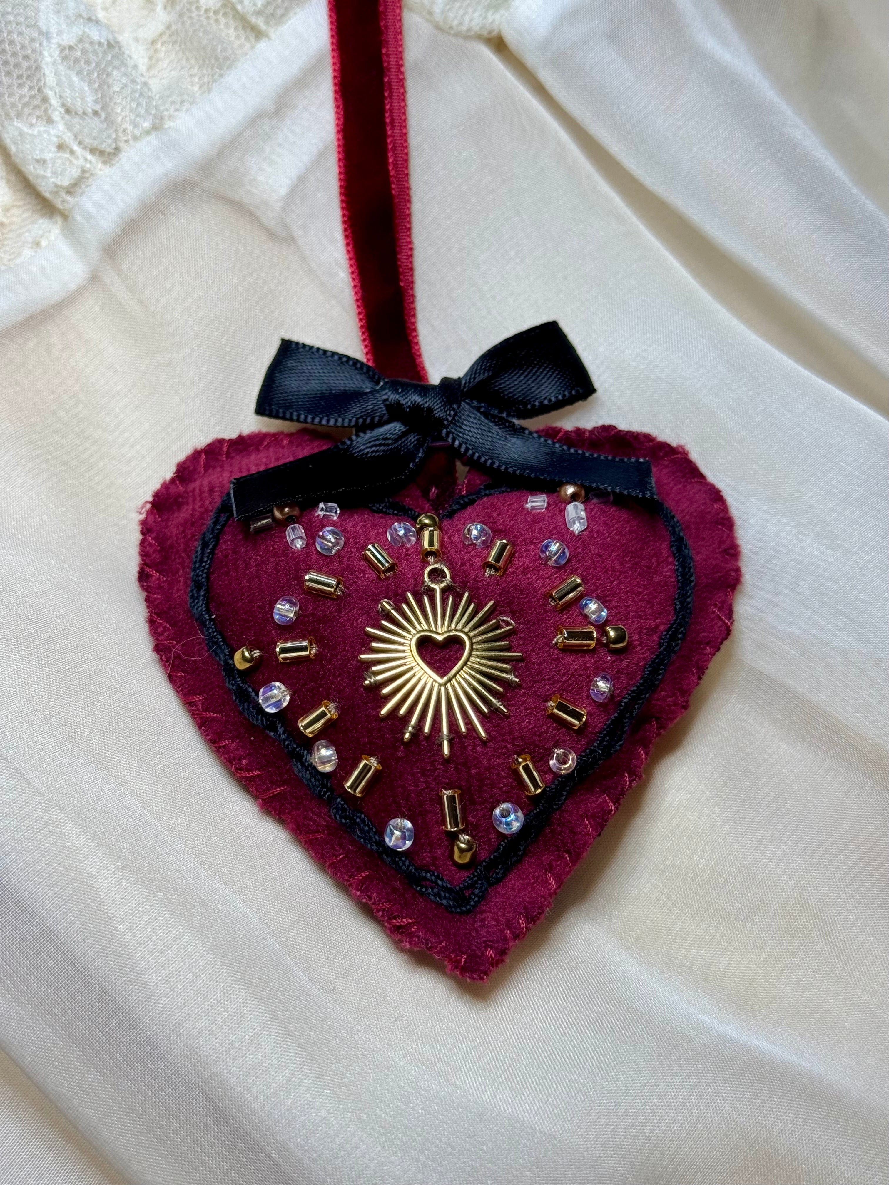 Decorative heart ornament with embellishments on a white fabric background
