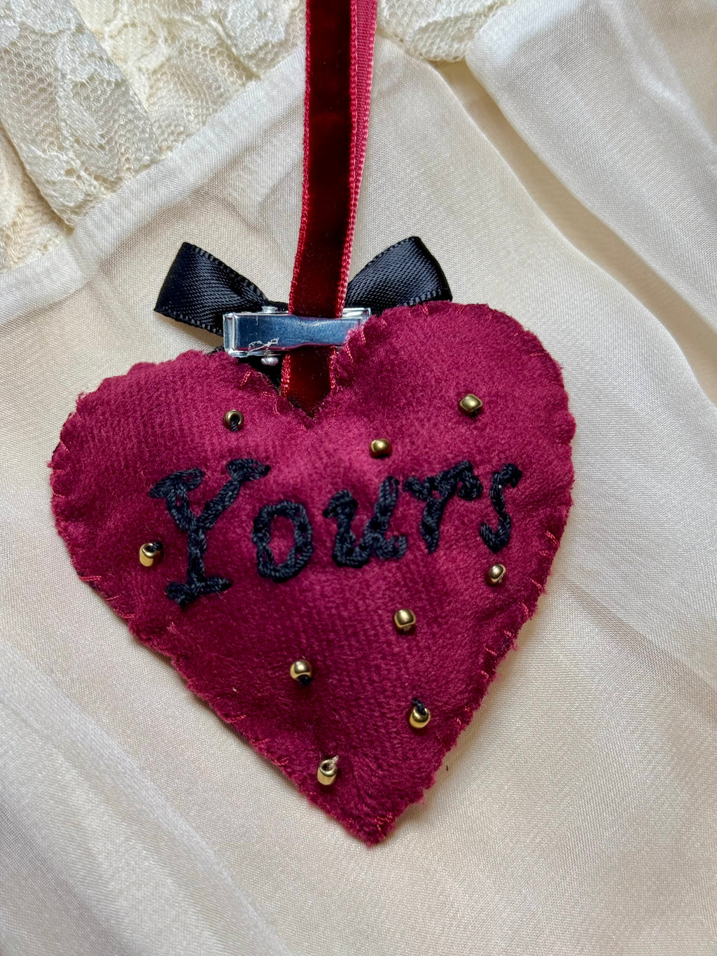 Heart-shaped fabric ornament with 'Yours' text on a white background