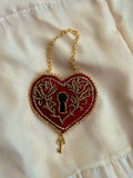 Heart-shaped keychain with lock design on a white fabric background
