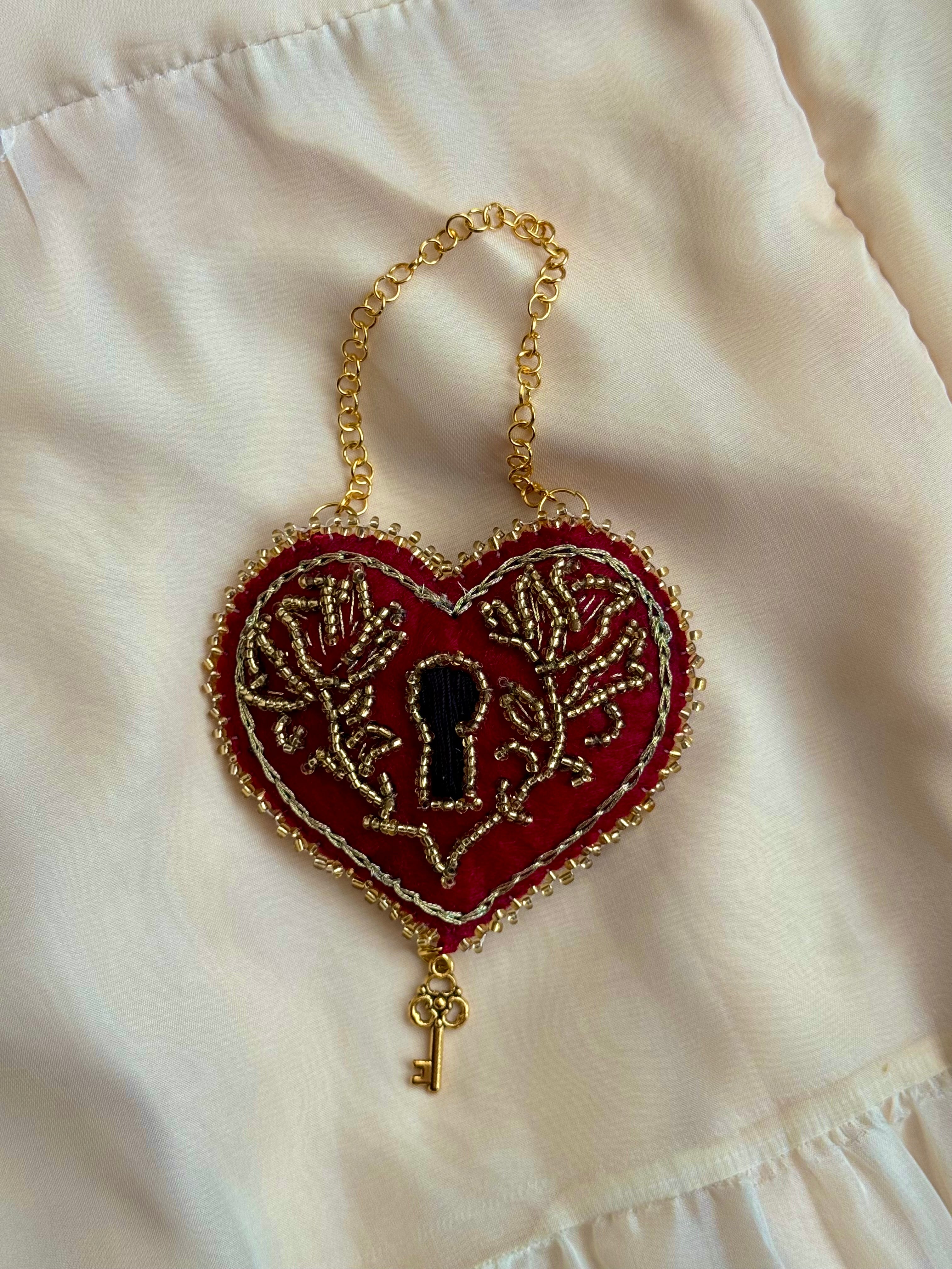 Heart-shaped keychain with lock design on a white fabric background