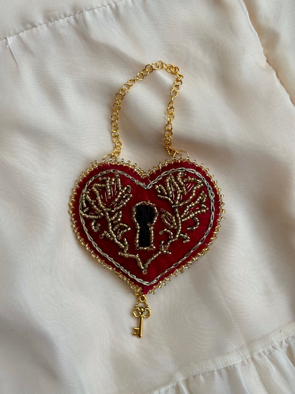 Heart-shaped keychain with key design on a white fabric background