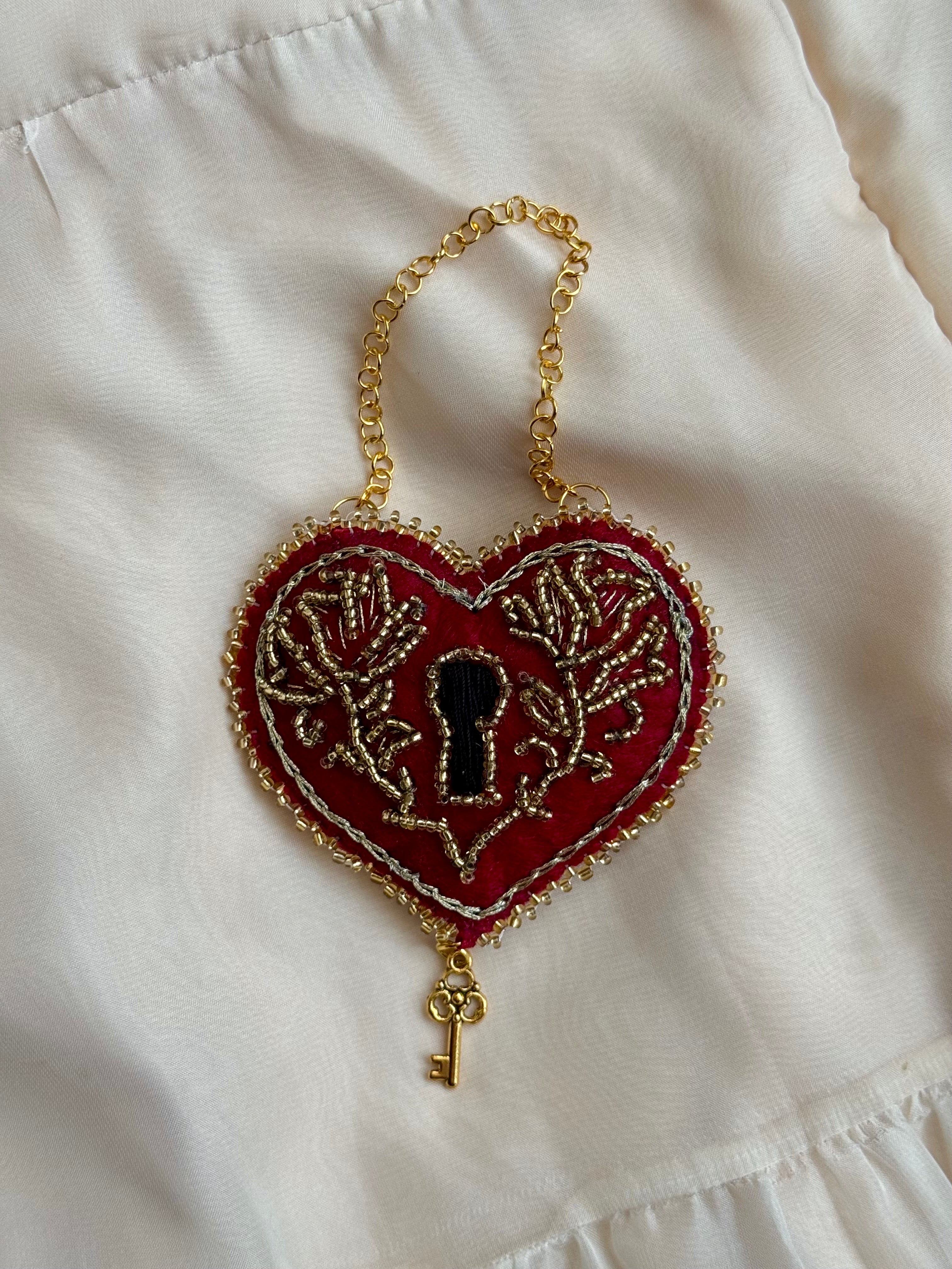 Heart-shaped keychain with key design on a white fabric background