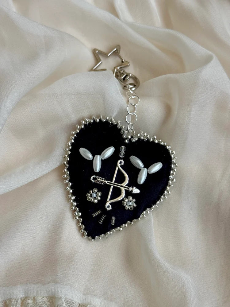 Heart-shaped keychain with decorative elements on a white fabric background