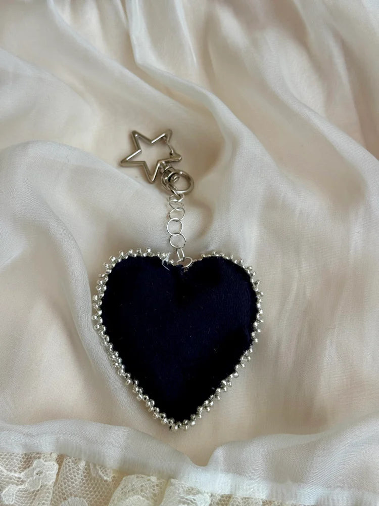 Black heart-shaped pendant with star charm on a white fabric background